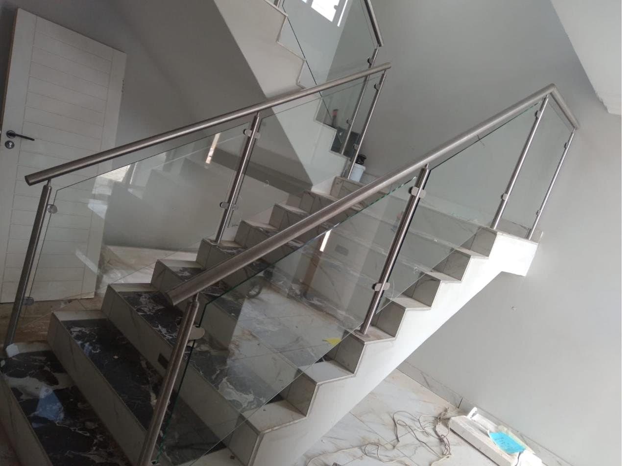 Frameless glass balustrade with stainless steel handrail on a marble staircase